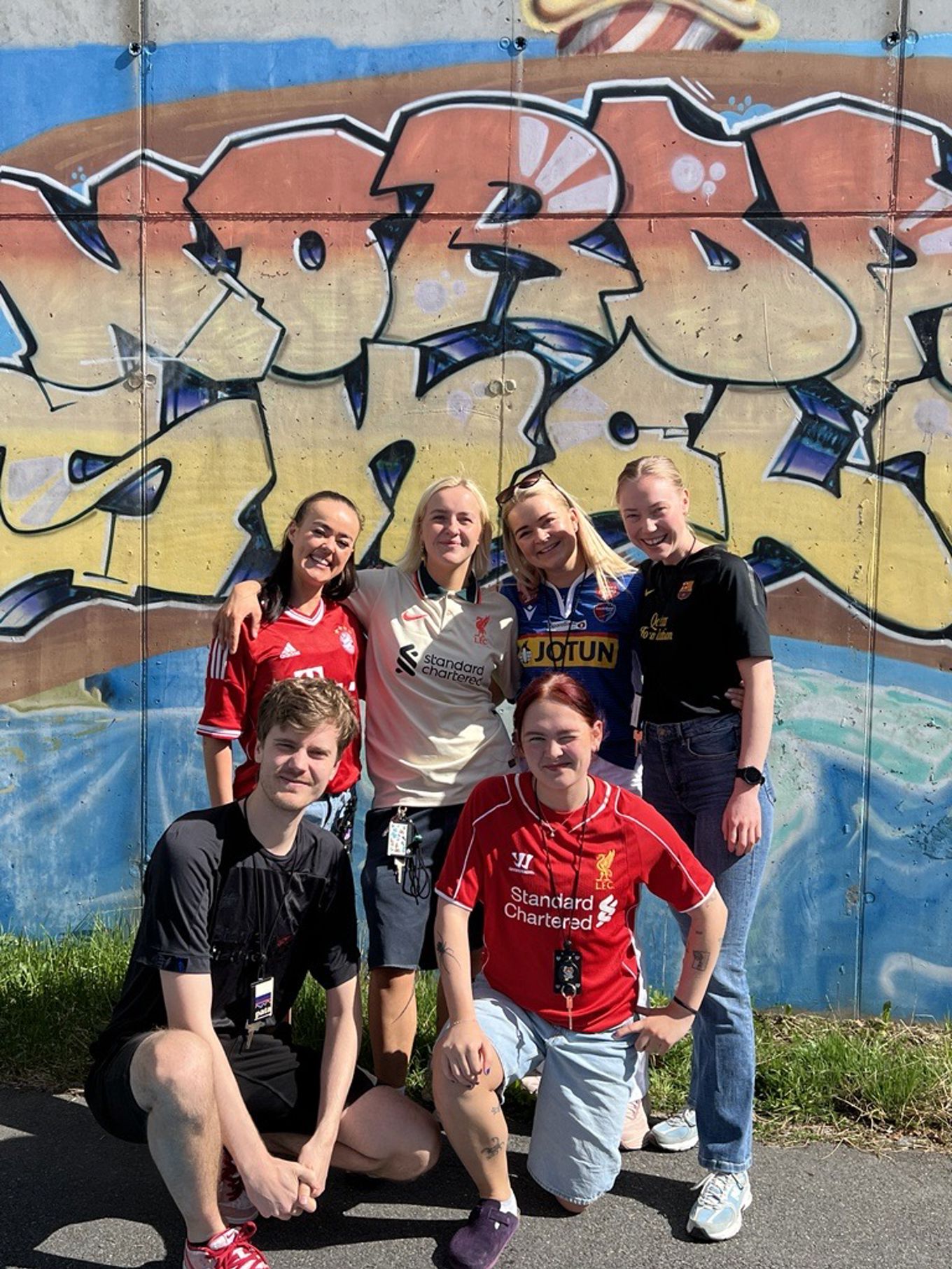 En gruppe mennesker som poserer for et bilde foran en vegg En gruppe mennesker som poserer for et bilde foran en vegg